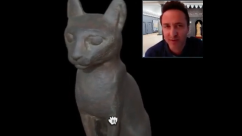 curator and sculpture of seated cat.