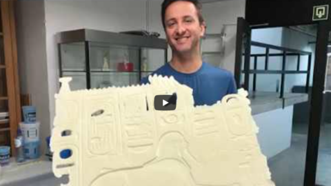 curator holds up sample cast of egyptian relief.