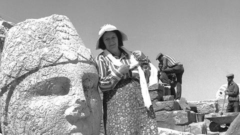 Theresa Goell standing next to a large stone head in the field.