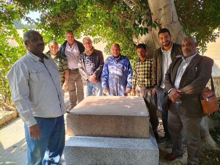 A team of eight men posing around the newly restored George Reisner tombstone.