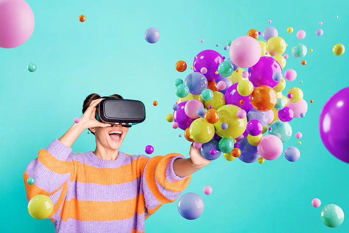 A person using a virtual-reality headset interacts with multicolor computer-rendered bubbles.