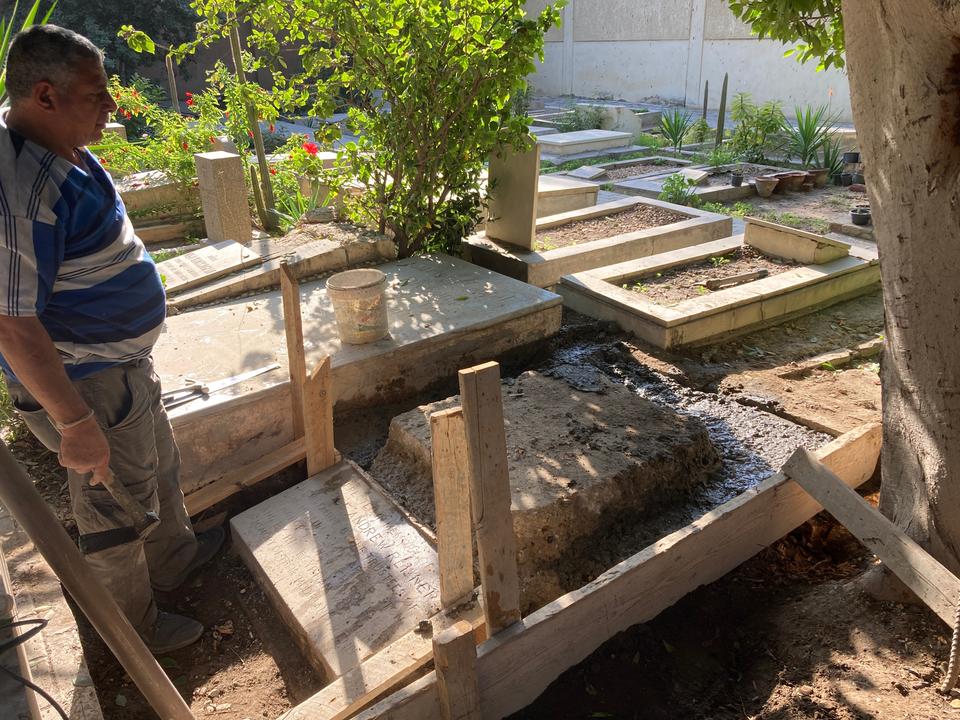 Man surveying the newly carved stone base surrounded by lush greenery.