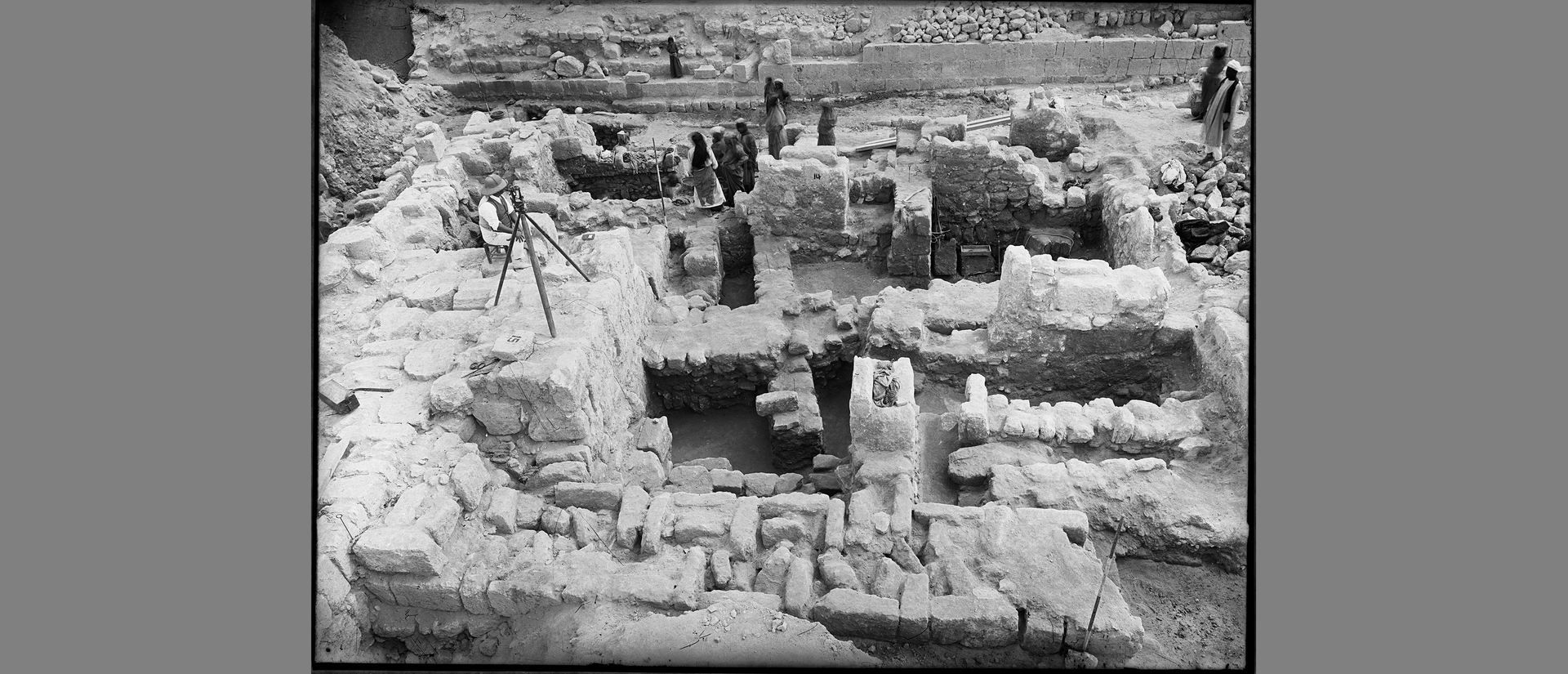 george reisner with tripod at excavation site with others.