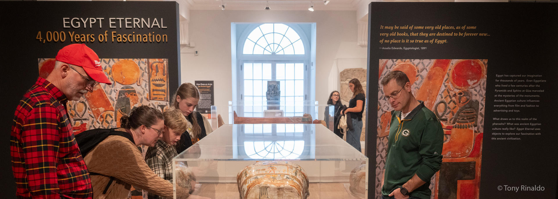 visitors gather around mummy coffin.