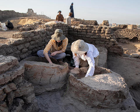two archaeologists excavating large structures.