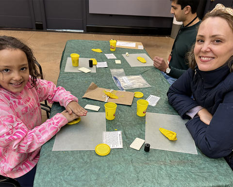 smiling kid presses clay with 2 adults in gallery.