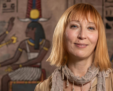smiling rita lucarelli in front of egyptian design.